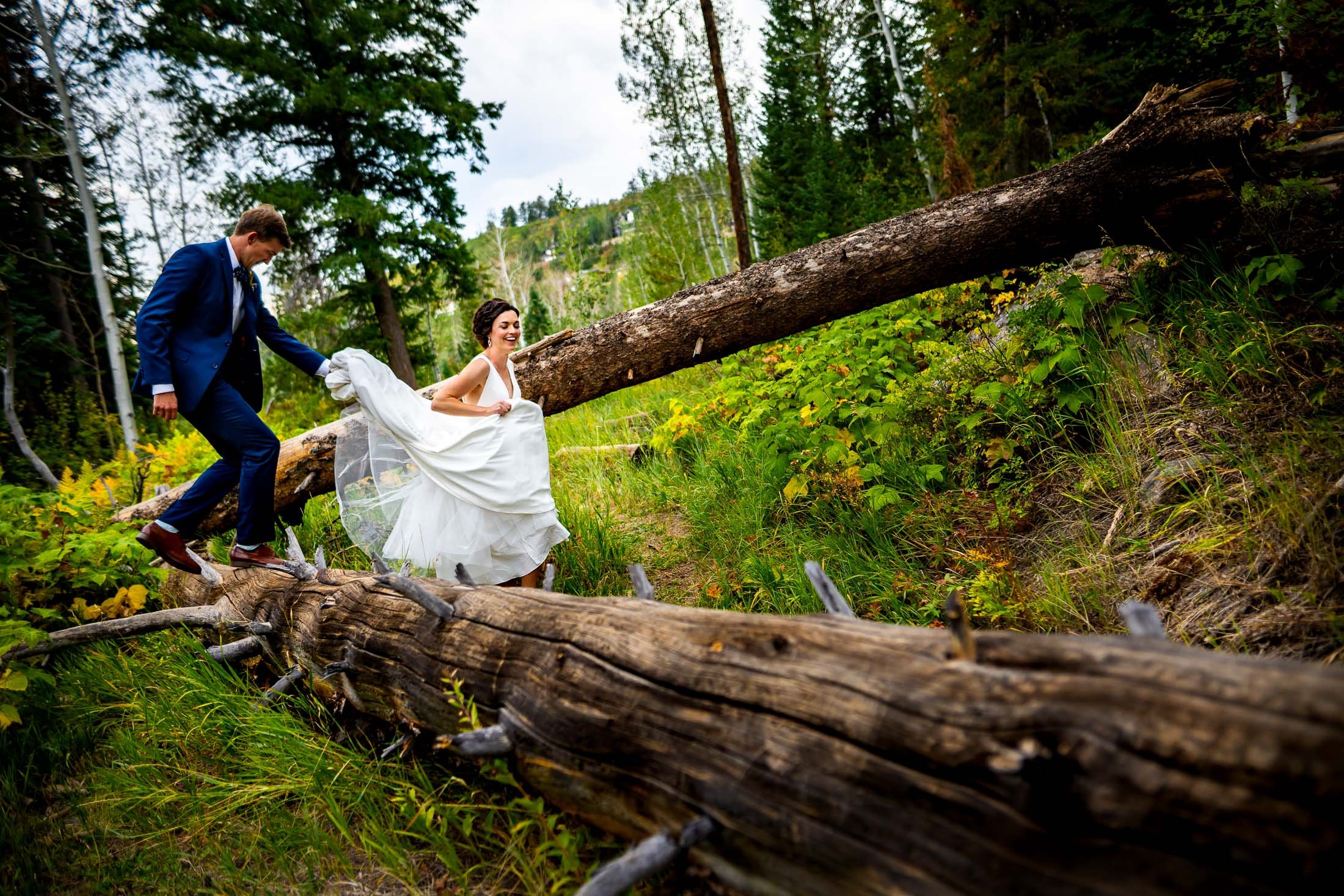 Bride and groom walk together over fallen logs in a forest, wedding, wedding photos, wedding photography, wedding photographer, wedding inspiration, wedding photo inspiration, wedding portraits, wedding ceremony, wedding reception, mountain wedding, Catholic Church wedding, Catholic Church wedding photos, Catholic Church wedding photography, Catholic Church wedding photographer, Catholic Church wedding inspiration, Catholic Church wedding venue, Steamboat Springs wedding, Steamboat Springs wedding photos, Steamboat Springs wedding photography, Steamboat Springs wedding photographer, Colorado wedding, Colorado wedding photos, Colorado wedding photography, Colorado wedding photographer, Colorado mountain wedding, Colorado wedding inspiration