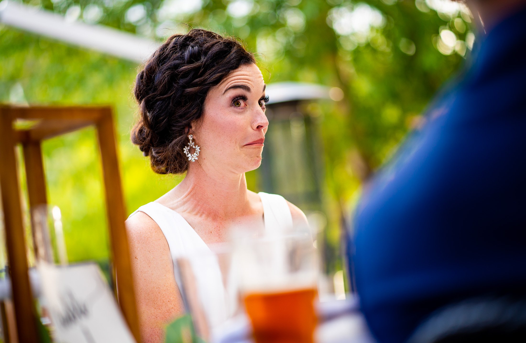 Bride and groom react to reception speeches while sitting on outdoor patio during the wedding reception, wedding, wedding photos, wedding photography, wedding photographer, wedding inspiration, wedding photo inspiration, wedding portraits, wedding ceremony, wedding reception, mountain wedding, Catholic Church wedding, Catholic Church wedding photos, Catholic Church wedding photography, Catholic Church wedding photographer, Catholic Church wedding inspiration, Catholic Church wedding venue, Steamboat Springs wedding, Steamboat Springs wedding photos, Steamboat Springs wedding photography, Steamboat Springs wedding photographer, Colorado wedding, Colorado wedding photos, Colorado wedding photography, Colorado wedding photographer, Colorado mountain wedding, Colorado wedding inspiration