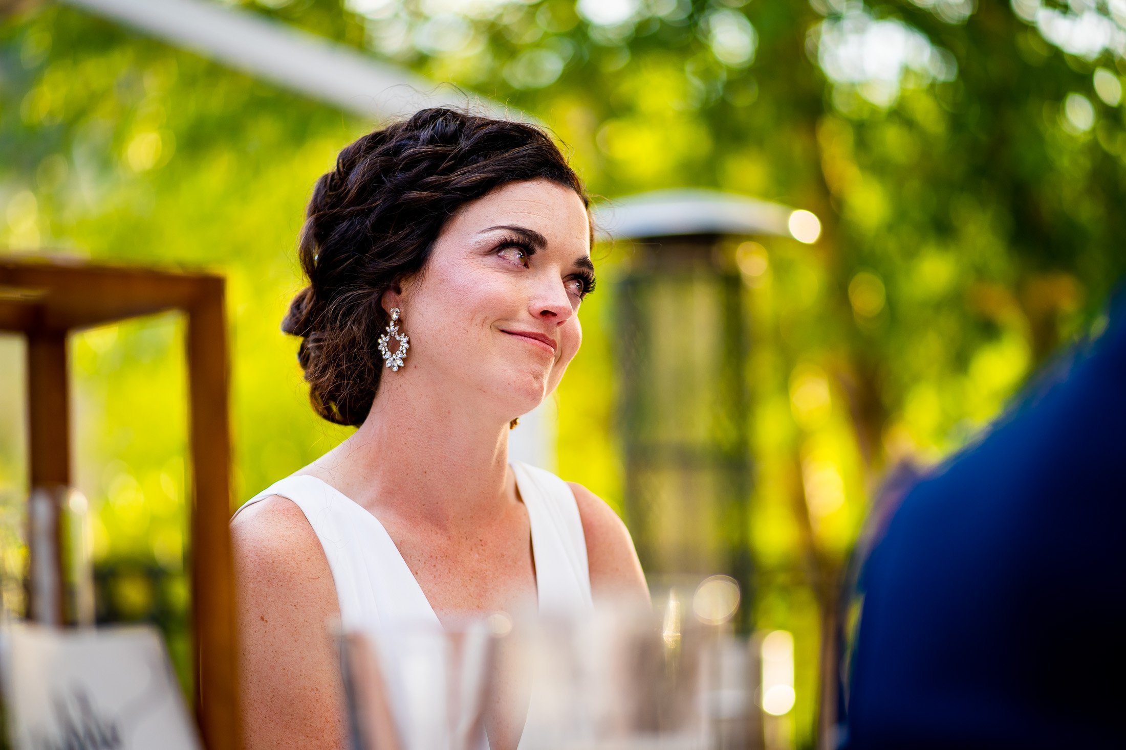 Bride and groom react to reception speeches while sitting on outdoor patio during the wedding reception, wedding, wedding photos, wedding photography, wedding photographer, wedding inspiration, wedding photo inspiration, wedding portraits, wedding ceremony, wedding reception, mountain wedding, Catholic Church wedding, Catholic Church wedding photos, Catholic Church wedding photography, Catholic Church wedding photographer, Catholic Church wedding inspiration, Catholic Church wedding venue, Steamboat Springs wedding, Steamboat Springs wedding photos, Steamboat Springs wedding photography, Steamboat Springs wedding photographer, Colorado wedding, Colorado wedding photos, Colorado wedding photography, Colorado wedding photographer, Colorado mountain wedding, Colorado wedding inspiration