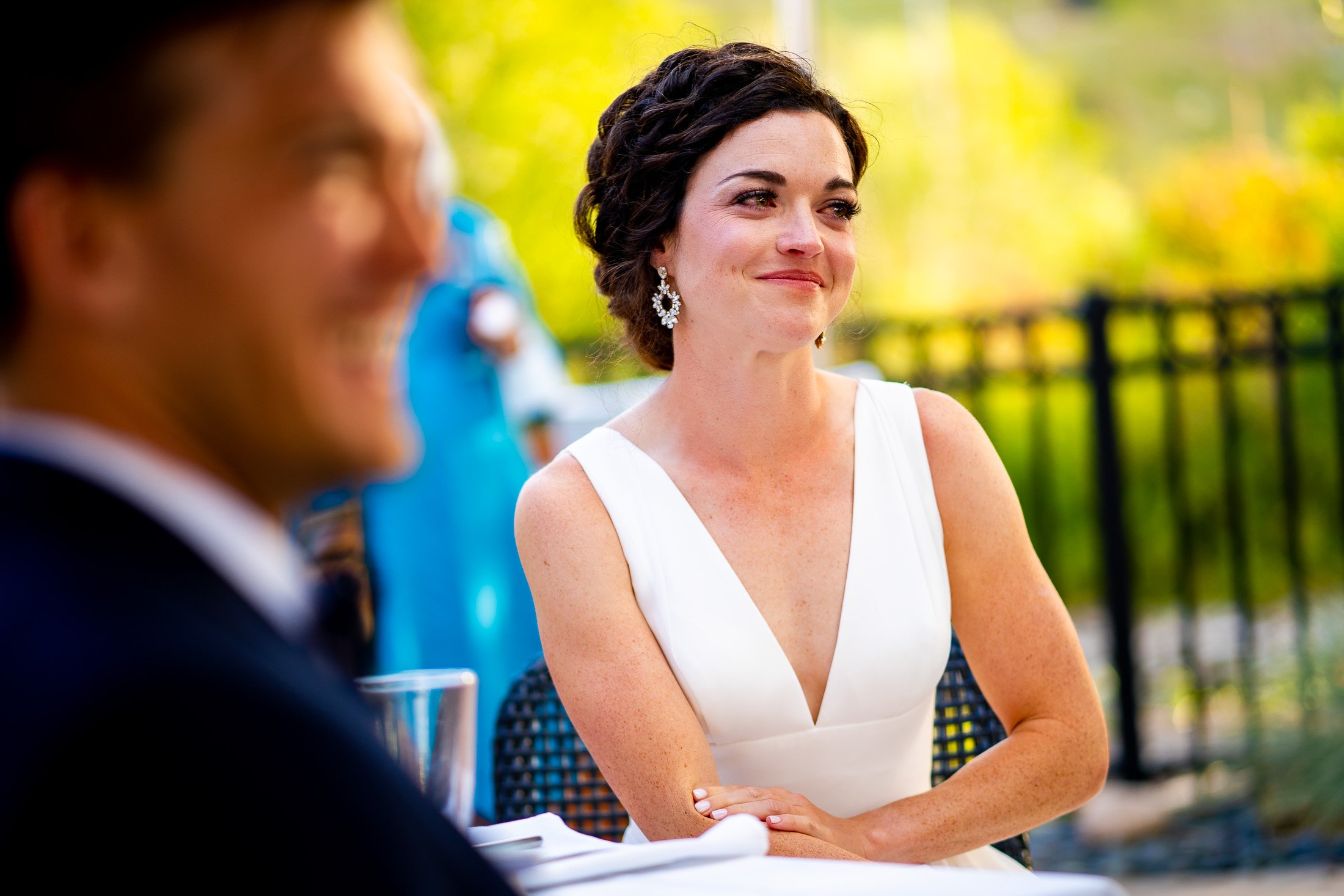 Bride and groom react to reception speeches while sitting on outdoor patio during the wedding reception, wedding, wedding photos, wedding photography, wedding photographer, wedding inspiration, wedding photo inspiration, wedding portraits, wedding ceremony, wedding reception, mountain wedding, Catholic Church wedding, Catholic Church wedding photos, Catholic Church wedding photography, Catholic Church wedding photographer, Catholic Church wedding inspiration, Catholic Church wedding venue, Steamboat Springs wedding, Steamboat Springs wedding photos, Steamboat Springs wedding photography, Steamboat Springs wedding photographer, Colorado wedding, Colorado wedding photos, Colorado wedding photography, Colorado wedding photographer, Colorado mountain wedding, Colorado wedding inspiration