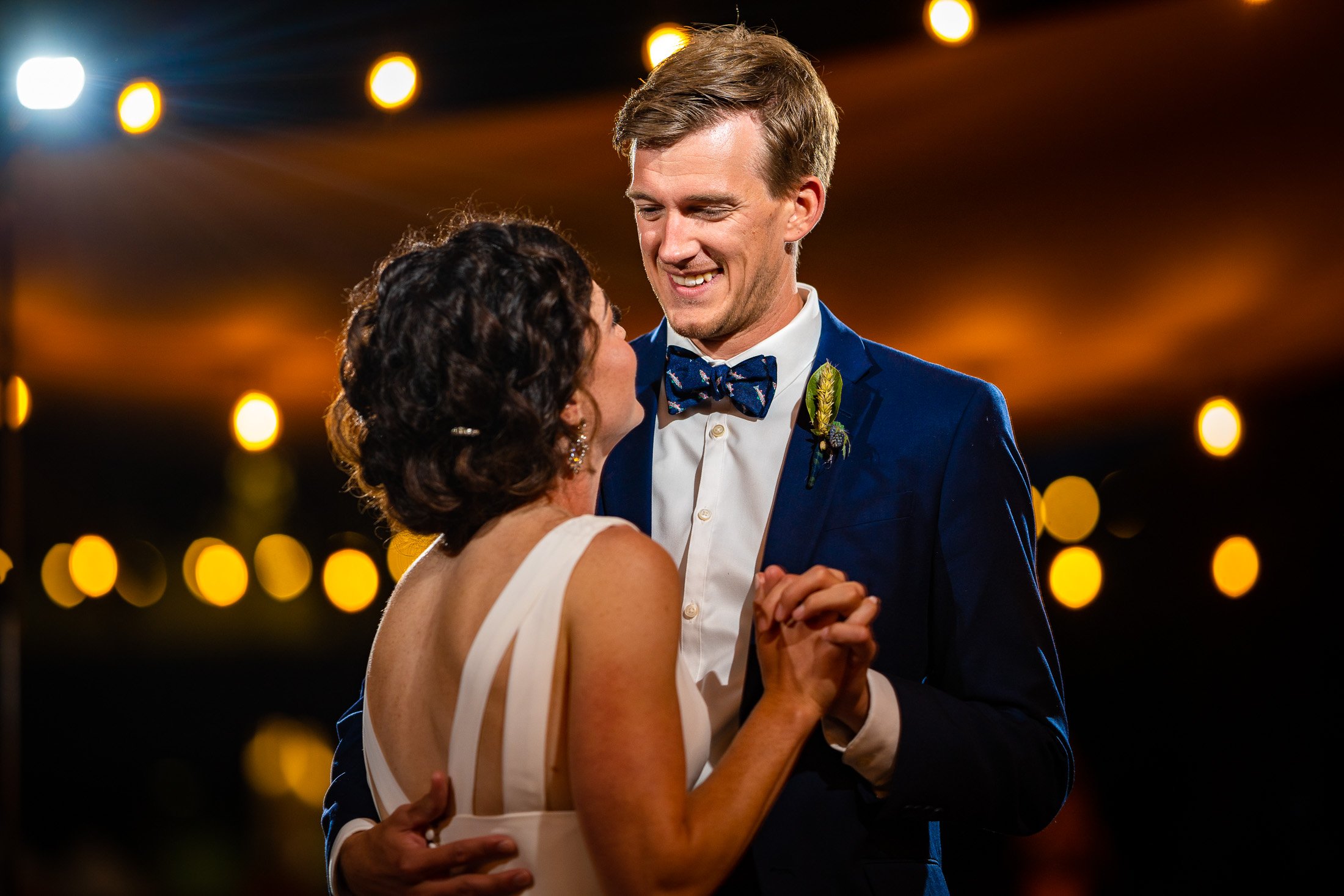 Bride and groom share their first dance on the outdoor patio under cafe lights at blue hour during their wedding reception, wedding, wedding photos, wedding photography, wedding photographer, wedding inspiration, wedding photo inspiration, wedding portraits, wedding ceremony, wedding reception, mountain wedding, Catholic Church wedding, Catholic Church wedding photos, Catholic Church wedding photography, Catholic Church wedding photographer, Catholic Church wedding inspiration, Catholic Church wedding venue, Steamboat Springs wedding, Steamboat Springs wedding photos, Steamboat Springs wedding photography, Steamboat Springs wedding photographer, Colorado wedding, Colorado wedding photos, Colorado wedding photography, Colorado wedding photographer, Colorado mountain wedding, Colorado wedding inspiration