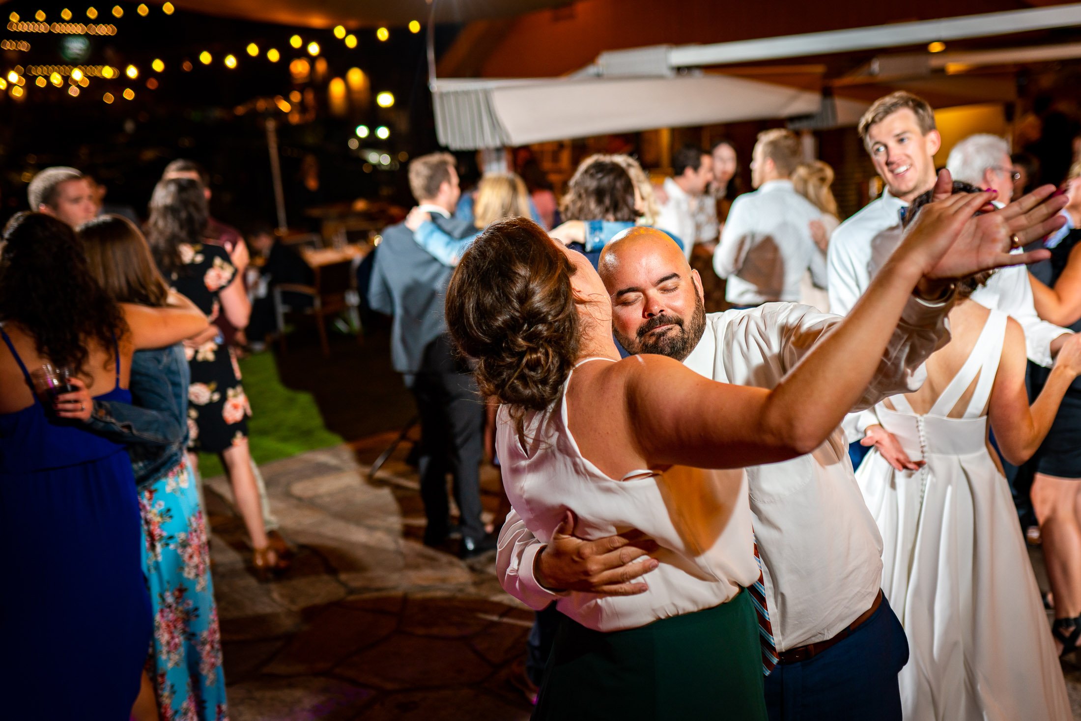 Guests dance to music on the outdoor patio under cafe lights during the wedding reception, wedding, wedding photos, wedding photography, wedding photographer, wedding inspiration, wedding photo inspiration, wedding portraits, wedding ceremony, wedding reception, mountain wedding, Catholic Church wedding, Catholic Church wedding photos, Catholic Church wedding photography, Catholic Church wedding photographer, Catholic Church wedding inspiration, Catholic Church wedding venue, Steamboat Springs wedding, Steamboat Springs wedding photos, Steamboat Springs wedding photography, Steamboat Springs wedding photographer, Colorado wedding, Colorado wedding photos, Colorado wedding photography, Colorado wedding photographer, Colorado mountain wedding, Colorado wedding inspiration