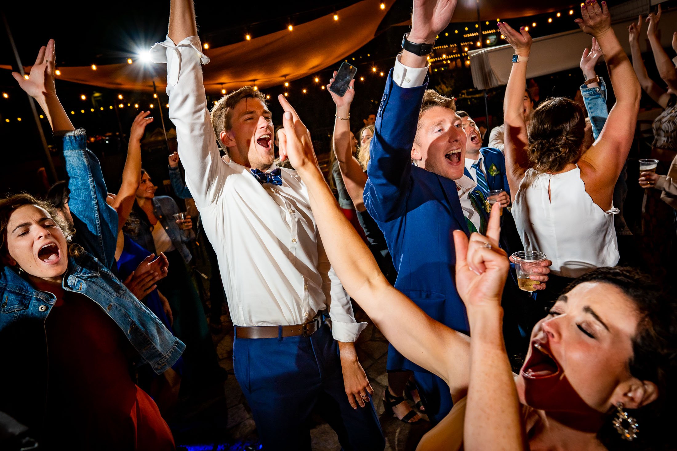 Guests dance to music on the outdoor patio under cafe lights during the wedding reception, wedding, wedding photos, wedding photography, wedding photographer, wedding inspiration, wedding photo inspiration, wedding portraits, wedding ceremony, wedding reception, mountain wedding, Catholic Church wedding, Catholic Church wedding photos, Catholic Church wedding photography, Catholic Church wedding photographer, Catholic Church wedding inspiration, Catholic Church wedding venue, Steamboat Springs wedding, Steamboat Springs wedding photos, Steamboat Springs wedding photography, Steamboat Springs wedding photographer, Colorado wedding, Colorado wedding photos, Colorado wedding photography, Colorado wedding photographer, Colorado mountain wedding, Colorado wedding inspiration