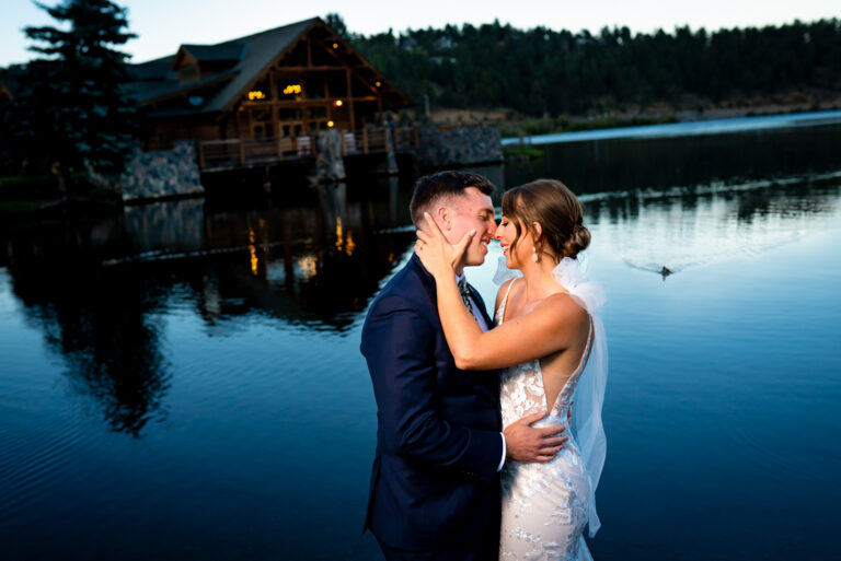 A bride and groom embrace in front of the Evergreen Lake House during a portrait session at their fall wedding in Evergreen, Colorado