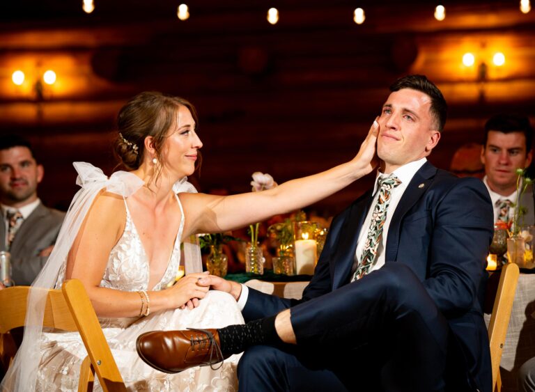 A bride gently touches the face of a groom captured in an intimate documentary wedding photography style at the Evergreen Lake House in Evergreen, Colorado