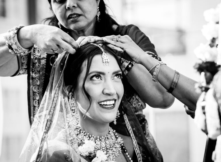 A bride has a decorative piece added to her hair, captured in a documentary wedding photography style as she gets ready for her wedding in Denver, Colorado