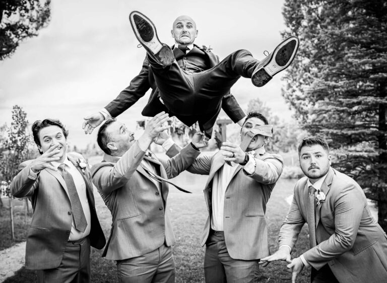 A groom is tossed in the air photographed in documentary style at a venue in Windsor, Colorado